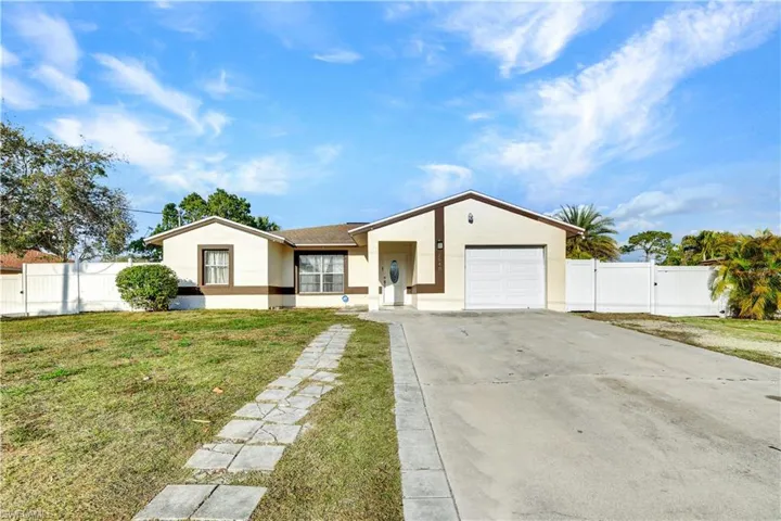 Ranch-style home featuring a gate, driveway, an attached garage, and stucco siding