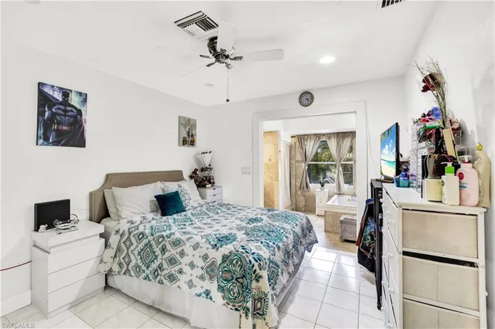 Bedroom featuring ceiling fan, light tile patterned flooring, ensuite bathroom, and recessed lighting