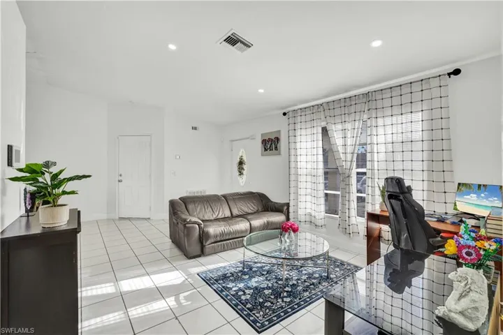 Living area with light tile patterned floors, an office area, and recessed lighting
