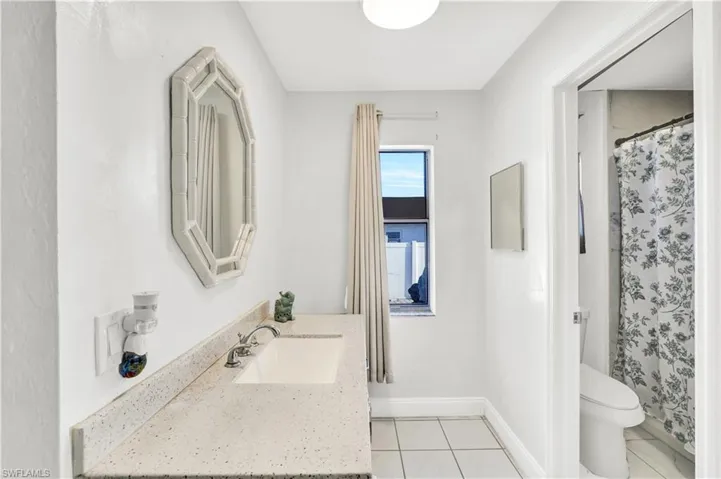 Bathroom featuring a shower with curtain, vanity, and light tile patterned flooring