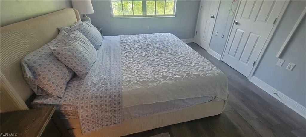 Bedroom featuring wood-finish flooring, light grey walls, and white trim