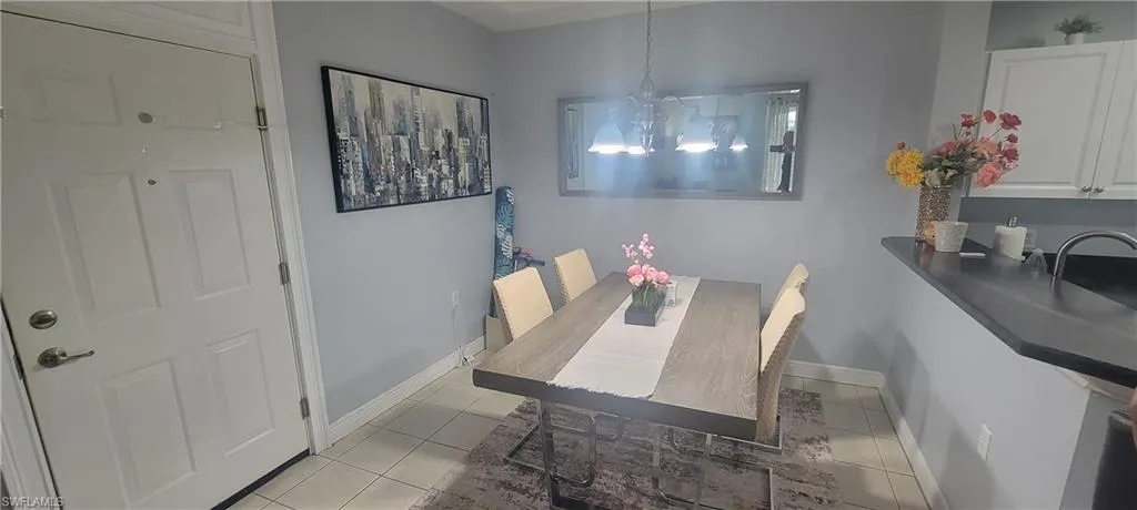 Dedicated dining area featuring a wood-finish table, a contemporary chandelier, a large wall mirror, and light gray wall paint