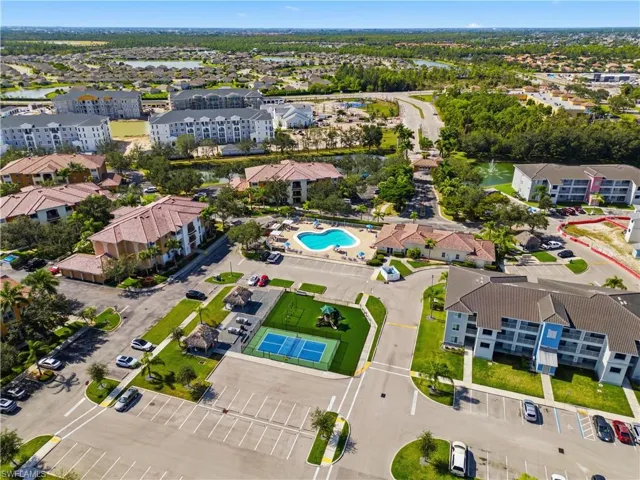 Aerial perspective showcasing multiple residential buildings, a central swimming pool, and a tennis court