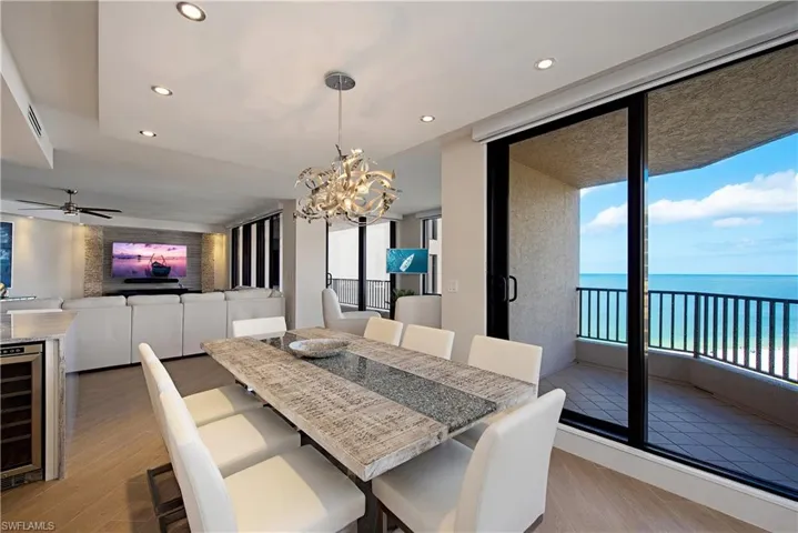 Dining area featuring light wood finished floors, a water view, recessed lighting, a chandelier, and wine cooler