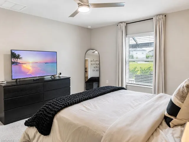 Bedroom featuring a ceiling fan with integrated lighting, a window with horizontal blinds and drapes, and neutral wall paint