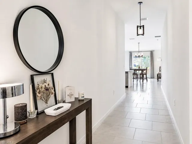 Bright interior hallway with light tile flooring and recessed lighting