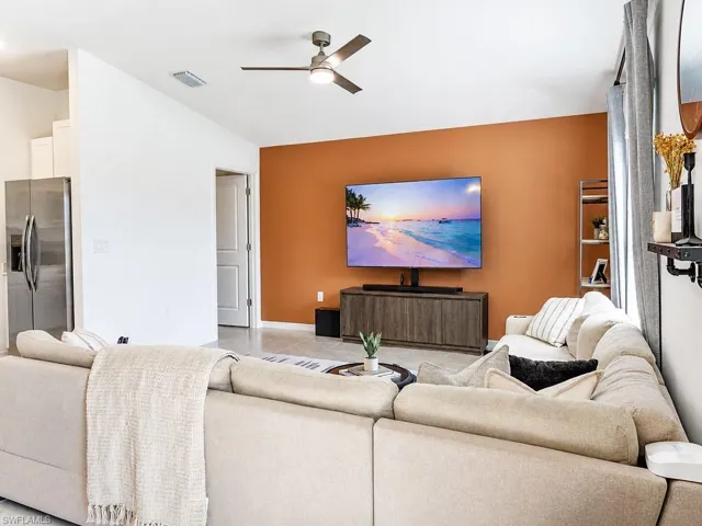 Spacious interior featuring a contemporary ceiling fan with integrated lighting, a contrasting accent wall, light-toned tile flooring