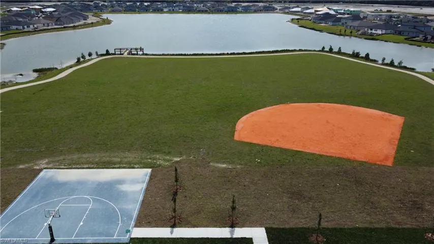 Expansive green space featuring a baseball field, basketball court, and lakeside walking path
