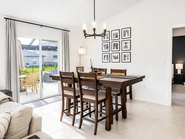 Dining area featuring light-toned tile flooring, a dark wood-finish dining table, and a contemporary chandelier