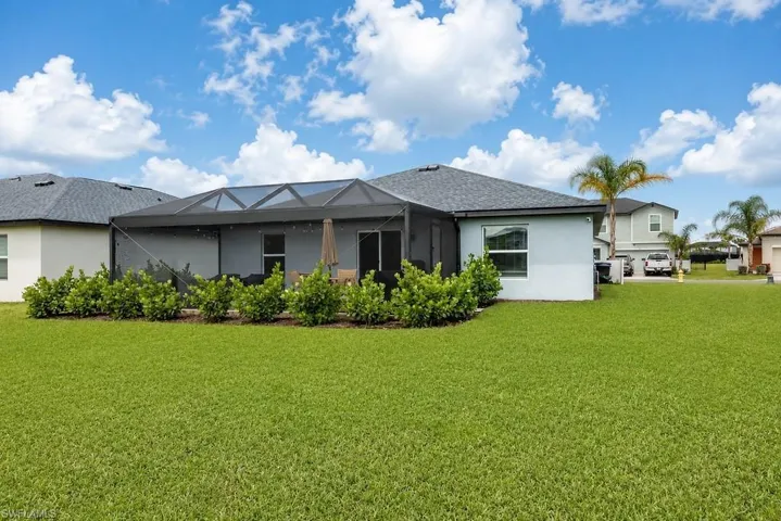 Expansive green lawn bordering a single-story residence with a screened lanai and mature landscaping