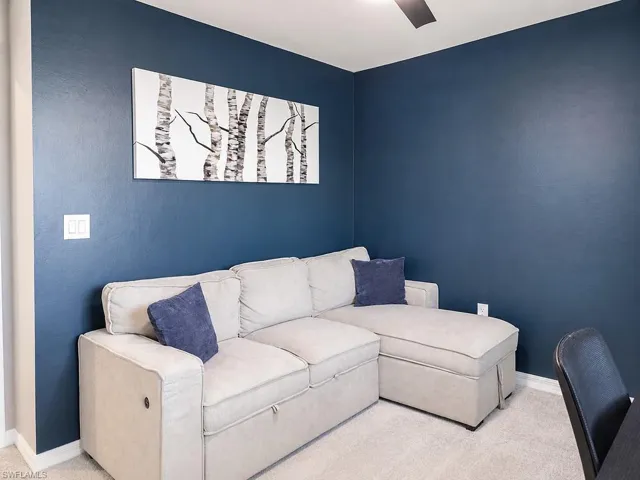 Room featuring dark blue walls, light beige carpeting, and white baseboards