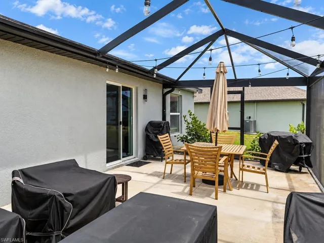 Screened lanai featuring a concrete patio, exterior sconce lighting, and string lighting