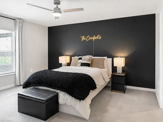 Bedroom featuring a dark accent wall, light gray carpeting, and a ceiling fan with integrated lighting