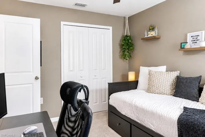 Neutral-toned room featuring a white paneled door, bi-fold closet doors, and wood-finish floating shelves
