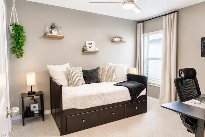 Neutral-toned room featuring light-colored carpeting, a window with blinds and drapes, and a ceiling fan with integrated lighting