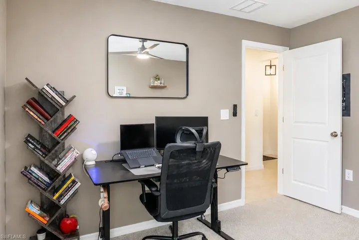 Neutral-toned room featuring light-colored carpet flooring and a ceiling fan with integrated lighting