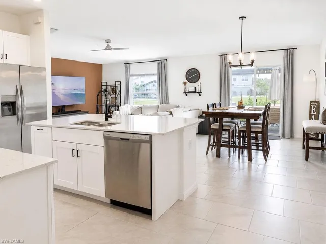 Kitchen island with a double basin sink, stainless steel dishwasher, and white cabinetry