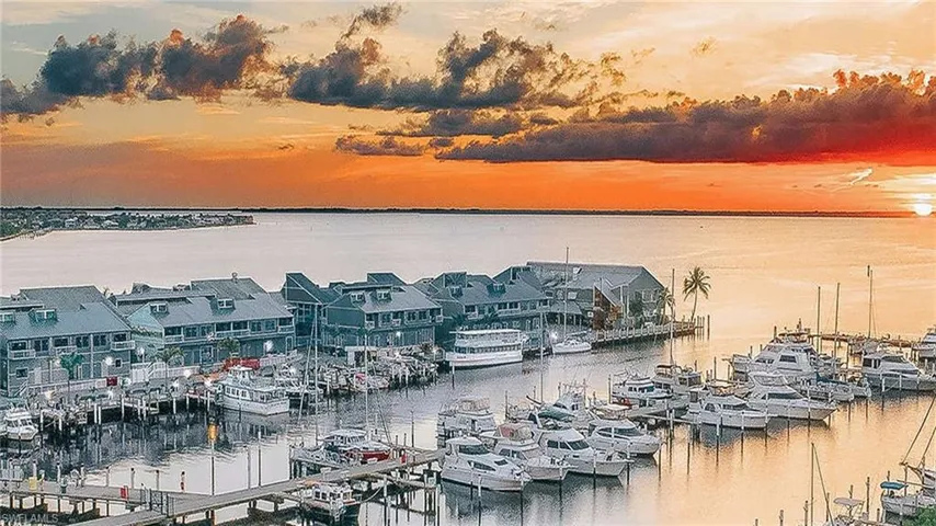 Waterfront marina with multiple boat slips and a collection of multi-story buildings featuring balconies