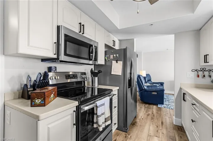 Kitchen featuring appliances with stainless steel finishes, white cabinets, light wood-type flooring, light countertops, and a ceiling fan
