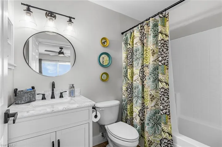 Full bath with shower / bath combination with curtain, vanity, and ceiling fan