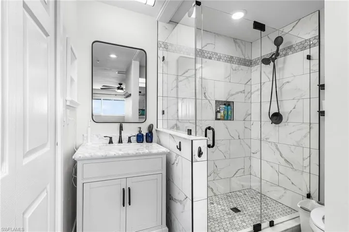 Full bath featuring a marble finish shower, vanity, and recessed lighting