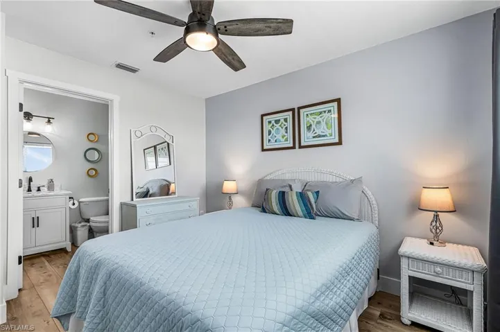 Bedroom with wood finished floors, a ceiling fan, and ensuite bathroom
