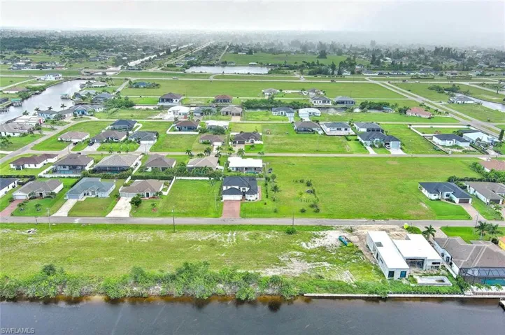 Aerial view of property and surrounding area with a nearby body of water and nearby suburban area