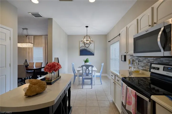 Contemporary kitchen featuring stainless steel appliances, a mosaic tile backsplash, and light-toned cabinetry