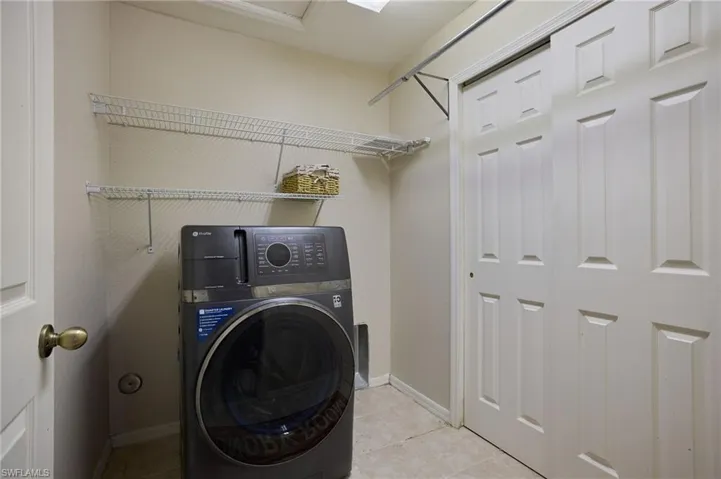 Laundry area featuring light-toned walls, tile flooring, and white wire shelving