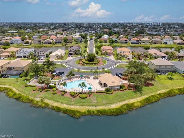 Community pool and clubhouse with surrounding residential properties, featuring a central roundabout, mature trees, and waterfront access
