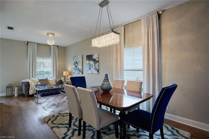 Open-concept living area with wood-finish flooring, neutral wall tones, and white window blinds