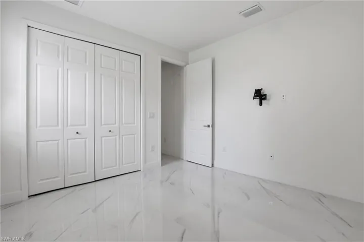Bright room featuring white walls, white paneled doors, and large format marble-look tile flooring