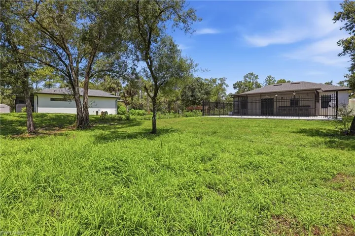 Expansive green space featuring mature trees and a fenced patio area
