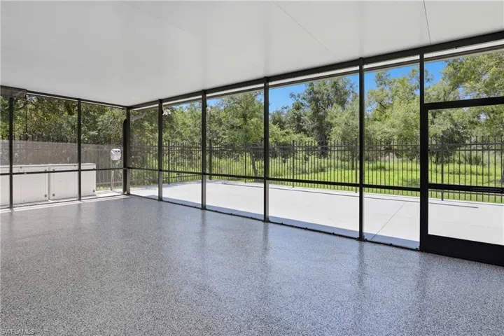 Expansive screened enclosure featuring a speckled epoxy floor, white ceiling, and a large concrete patio