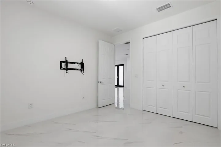 Bright room featuring large format tile flooring, a bi-fold closet, and a wall-mounted television bracket