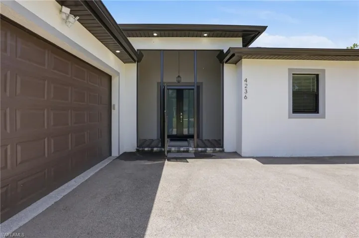 Contemporary exterior with a screened entry, brown paneled garage door, and a light-colored stucco finish