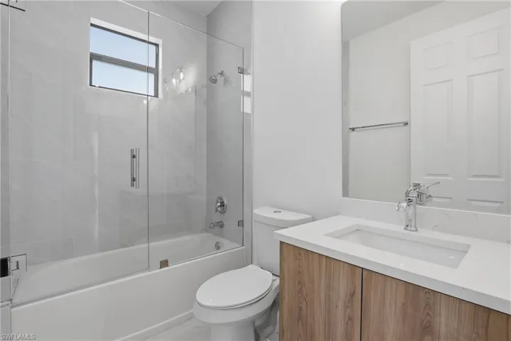 Bathroom with a wood-finish vanity, integrated rectangular sink, and chrome faucet