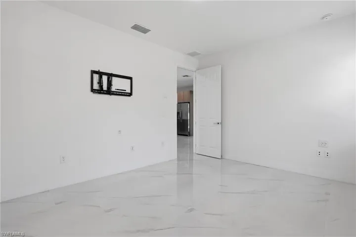Clean interior space featuring white walls and a large, light-colored tile floor
