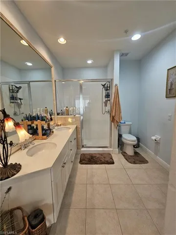 Bathroom featuring double vanity, a stall shower, light tile patterned floors, and recessed lighting