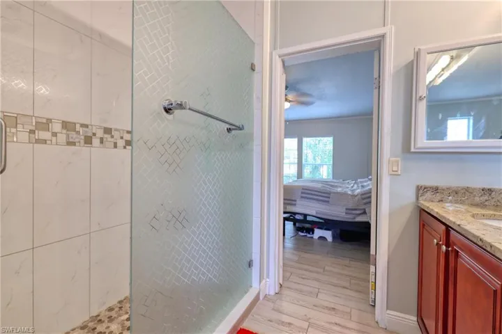 Bathroom with an enclosed shower, vanity, and hardwood / wood-style flooring