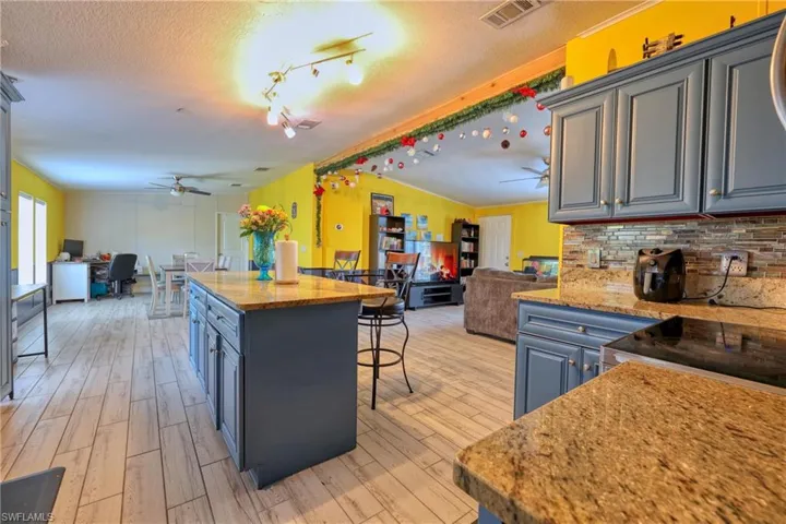 Kitchen with ceiling fan, a kitchen breakfast bar, a kitchen island, and light hardwood / wood-style flooring