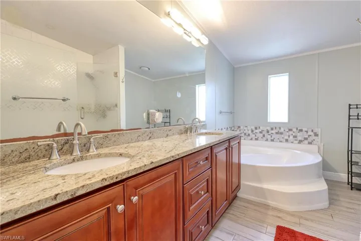 Bathroom featuring crown molding, vanity, plus walk in shower, and hardwood / wood-style flooring