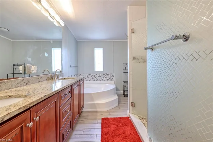 Bathroom with crown molding, wood-type flooring, separate shower and tub, and vanity