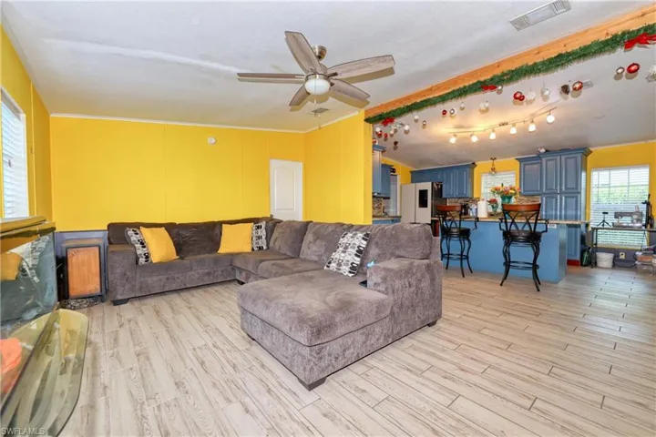 Living room with vaulted ceiling, ceiling fan, and light wood-type flooring