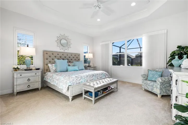 Carpeted bedroom with multiple windows, a raised ceiling, and ornamental molding