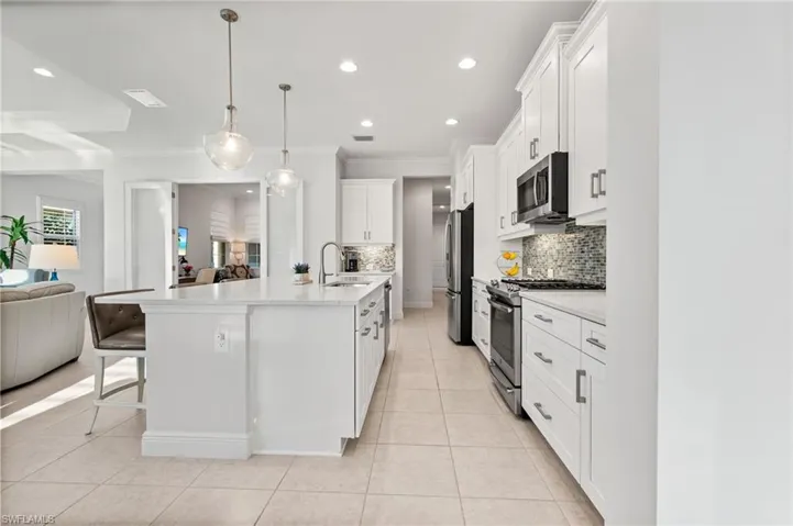 Kitchen featuring light tile patterned floors, a sink, stainless steel appliances, light countertops, and open floor plan