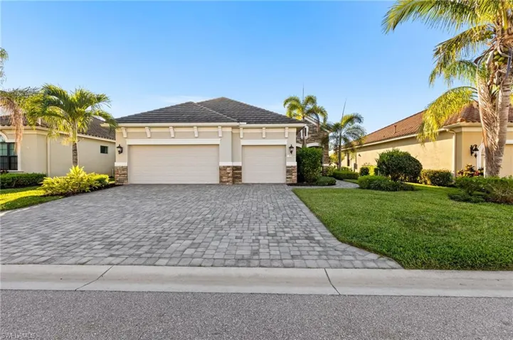 View of front of home with an attached garage, stucco siding, a front lawn, stone siding, and decorative driveway