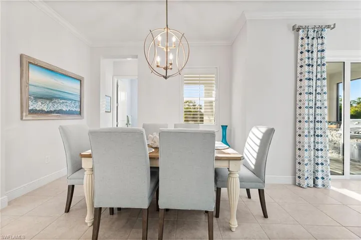 Dining room featuring light tile patterned floors, a healthy amount of sunlight, baseboards, and ornamental molding