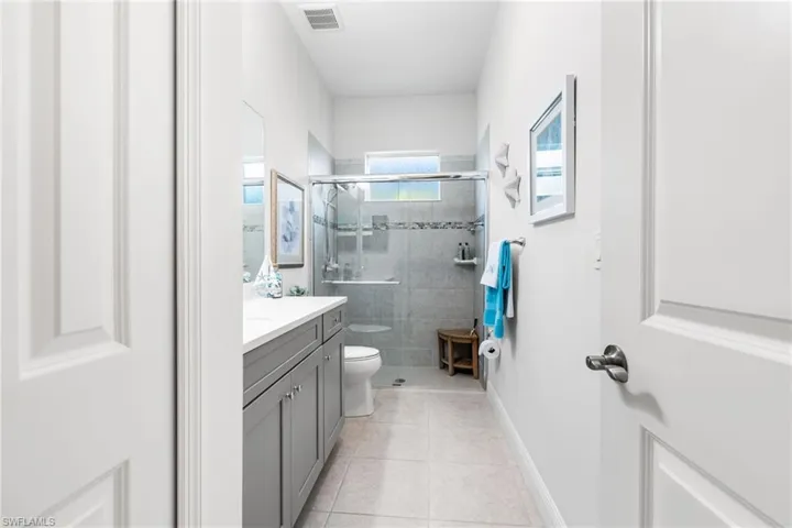Bathroom featuring vanity, visible vents, a stall shower, tile patterned floors, and toilet