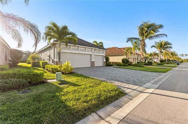 View of front of home with a garage, decorative driveway, a front yard, and stucco siding
